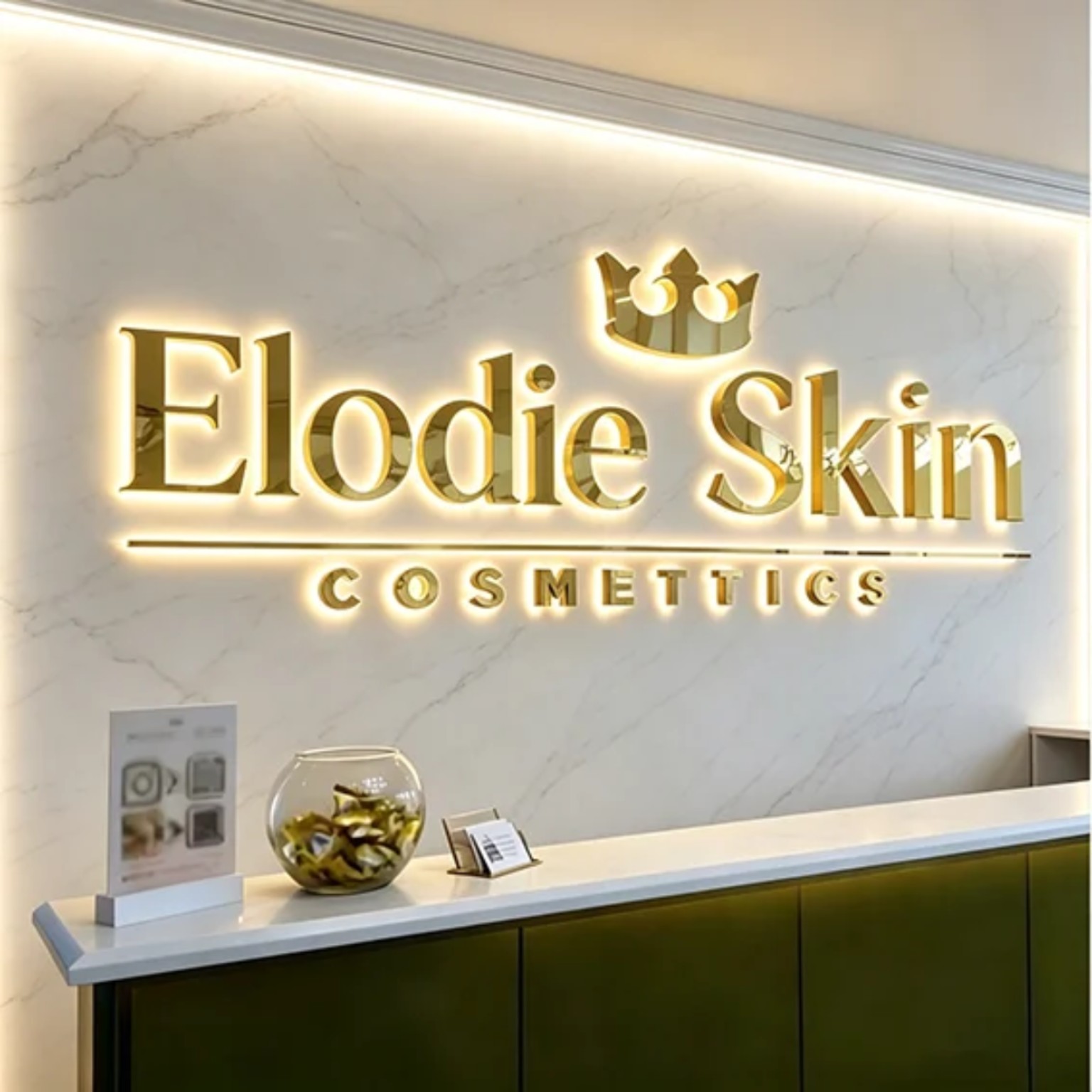 Gold mirrored dimensional lettering with warm halo lighting behind a cosmetics reception desk
